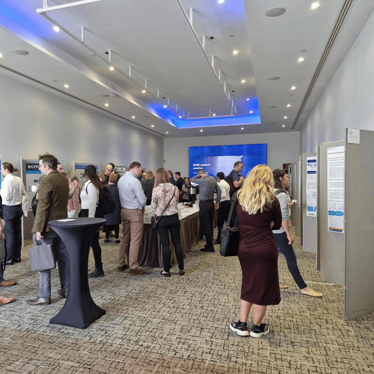 A room of people at a conference looking at scientific posters and mingling.