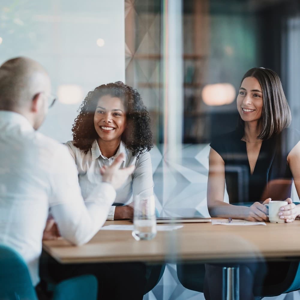 Group of business persons having a meeting behind a glass wall.