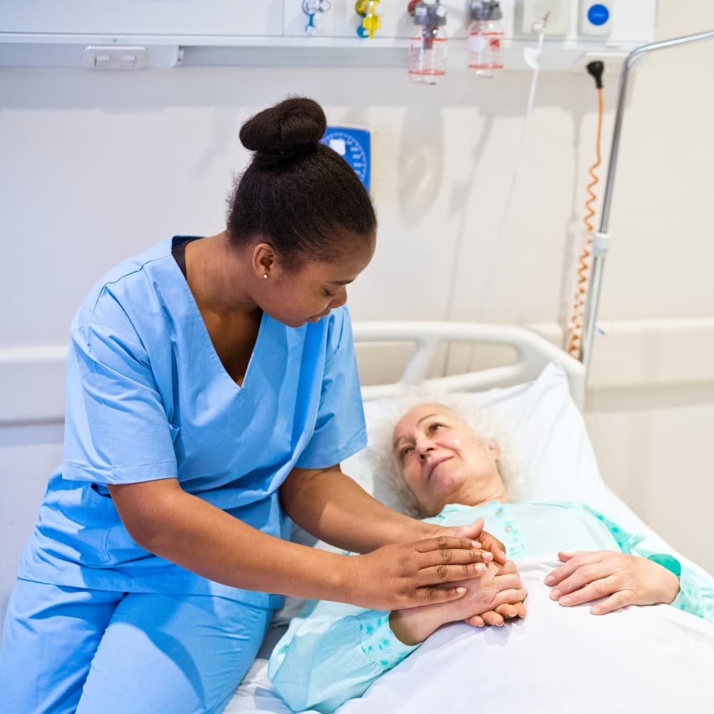 A medical professional comforts a patient lying in bed.
