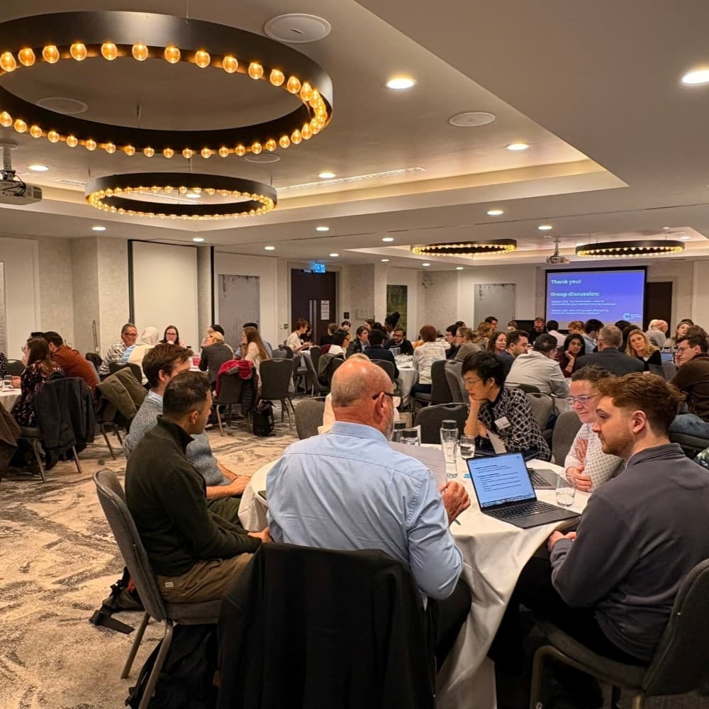 People seated at round tables in a large conference room.
